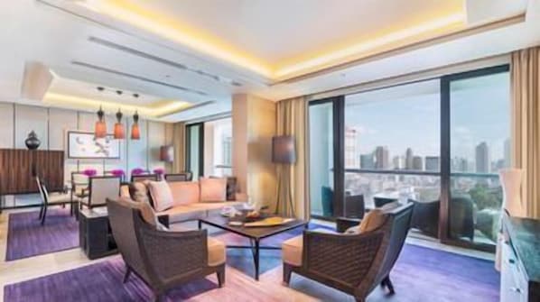 Una habitación de hotel moderna con un ventanal grande, un sofá, una mesita de café y un televisor.