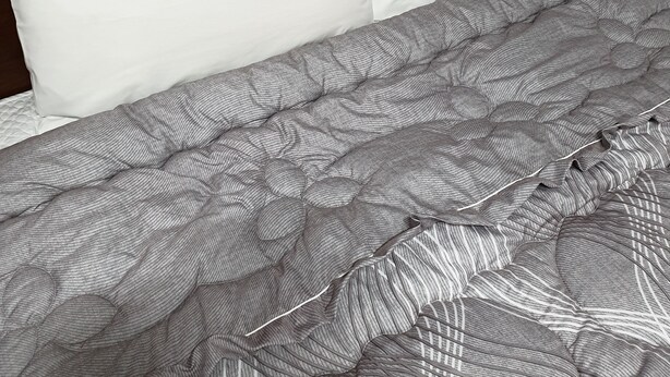 Una cama bien tendida con un edredón a rayas y dos almohadas con texto coreano.