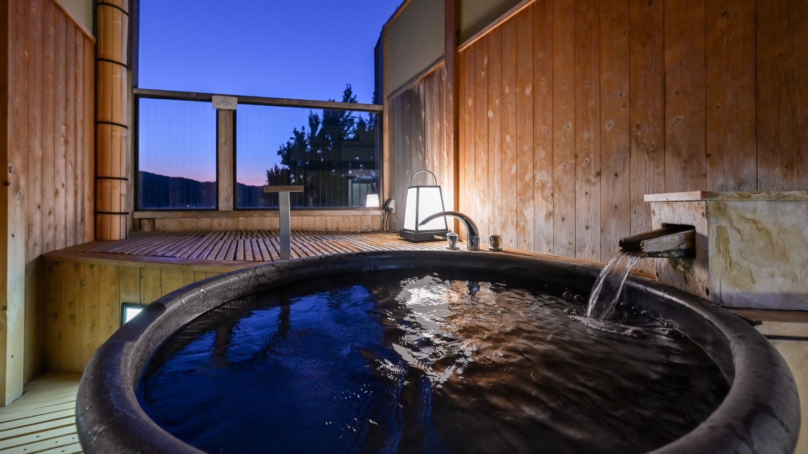 A wooden spa with a hot tub, wooden deck, and a view of the mountains.