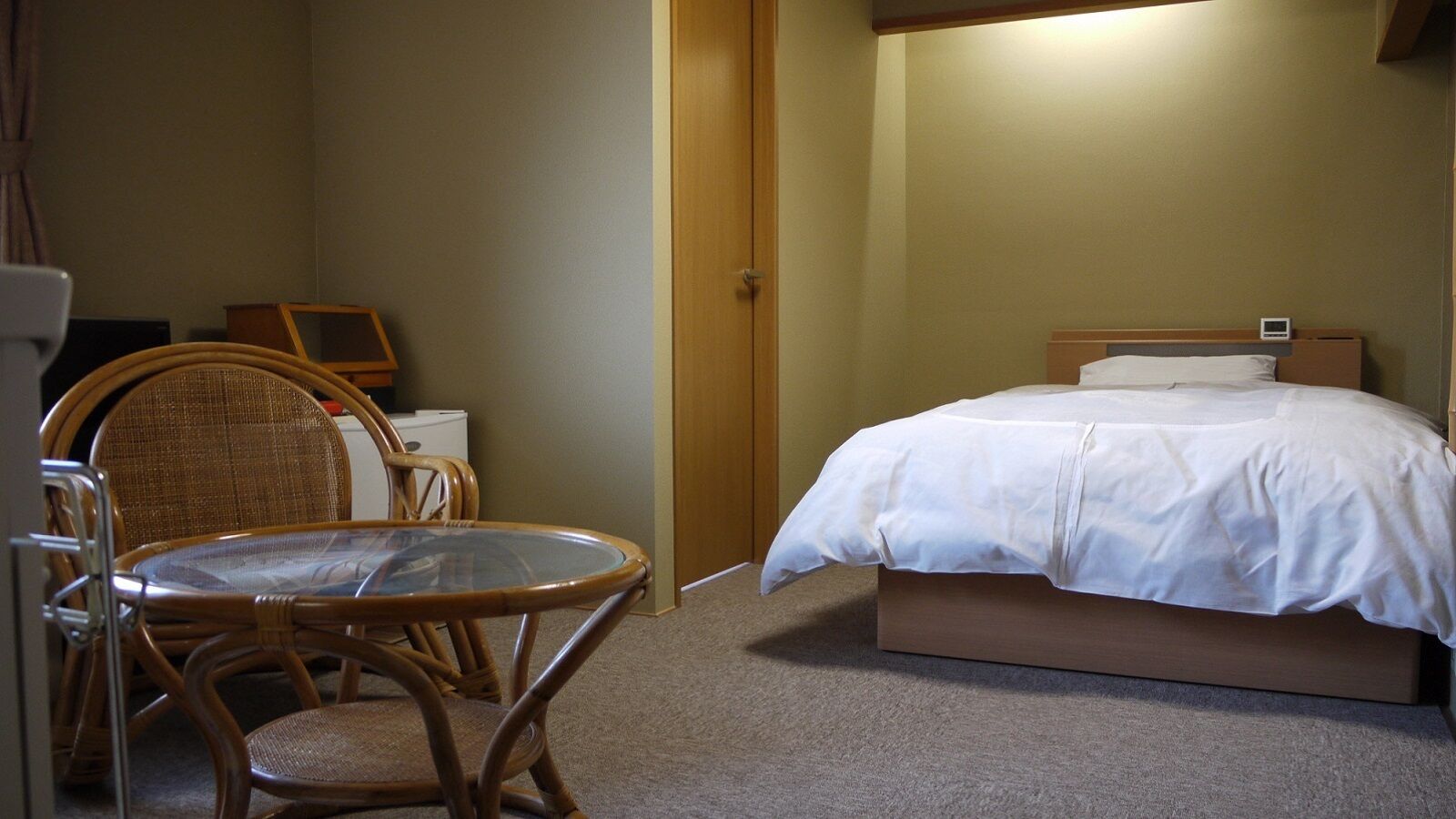 A hotel room with a bed, a chair, a table, and a desk.