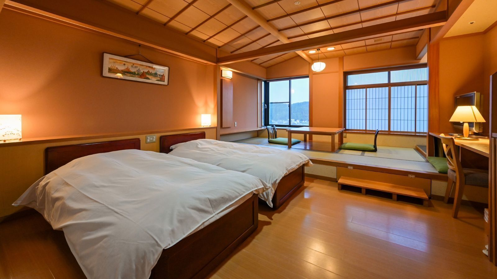 A hotel room with two beds, a small seating area, and a view of the outside.