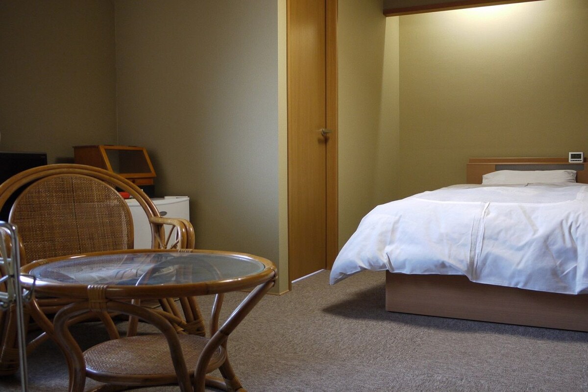 Une chambre d’hôtel avec un lit, une table ronde et une chaise.
