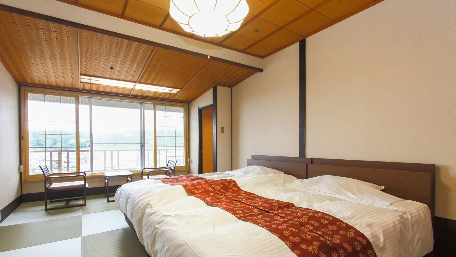 A hotel room with a large bed, a view through the window, and a wooden ceiling.