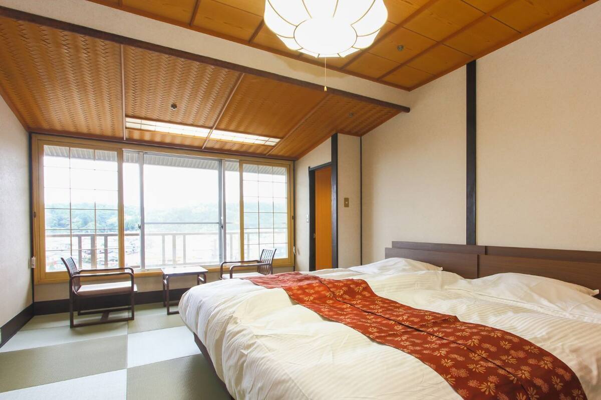 Una habitación de hotel con una cama grande, vistas por la ventana y un techo de madera.