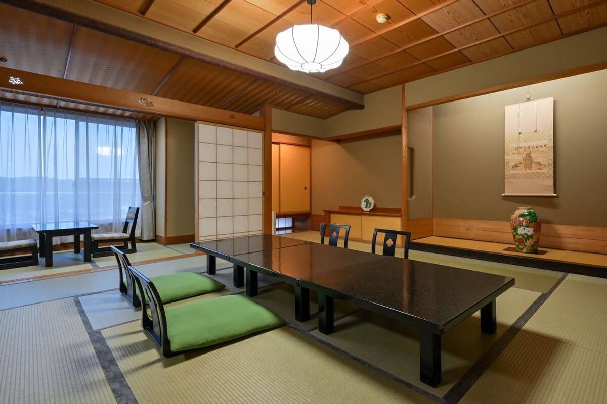 Una habitación tradicional japonesa con suelo de tatami, una mesa baja y puertas correderas shoji.