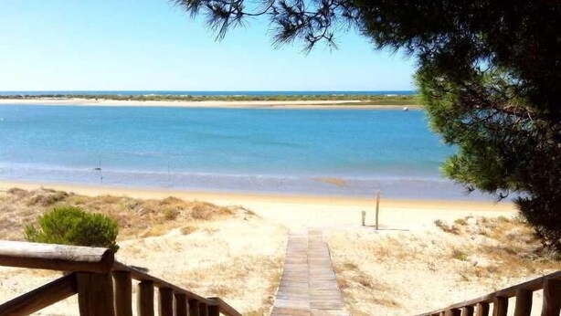 A wooden pathway leading to a beach with a clear view of the ocean.