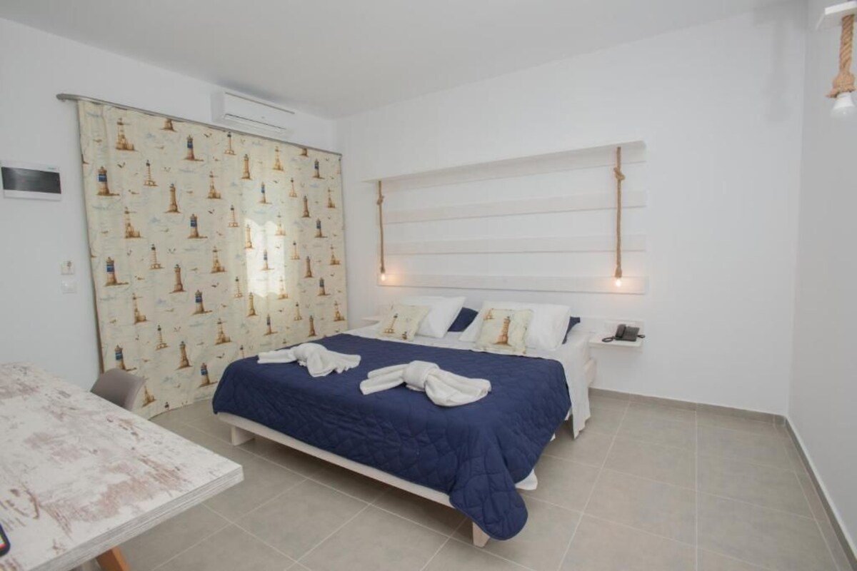 A bedroom with a bed, a table, and a curtain with a lighthouse pattern.