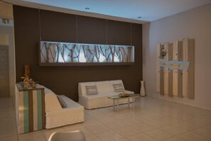 Un salón moderno con un sofá blanco, una mesa de centro de vidrio y un objeto decorativo a la izquierda.