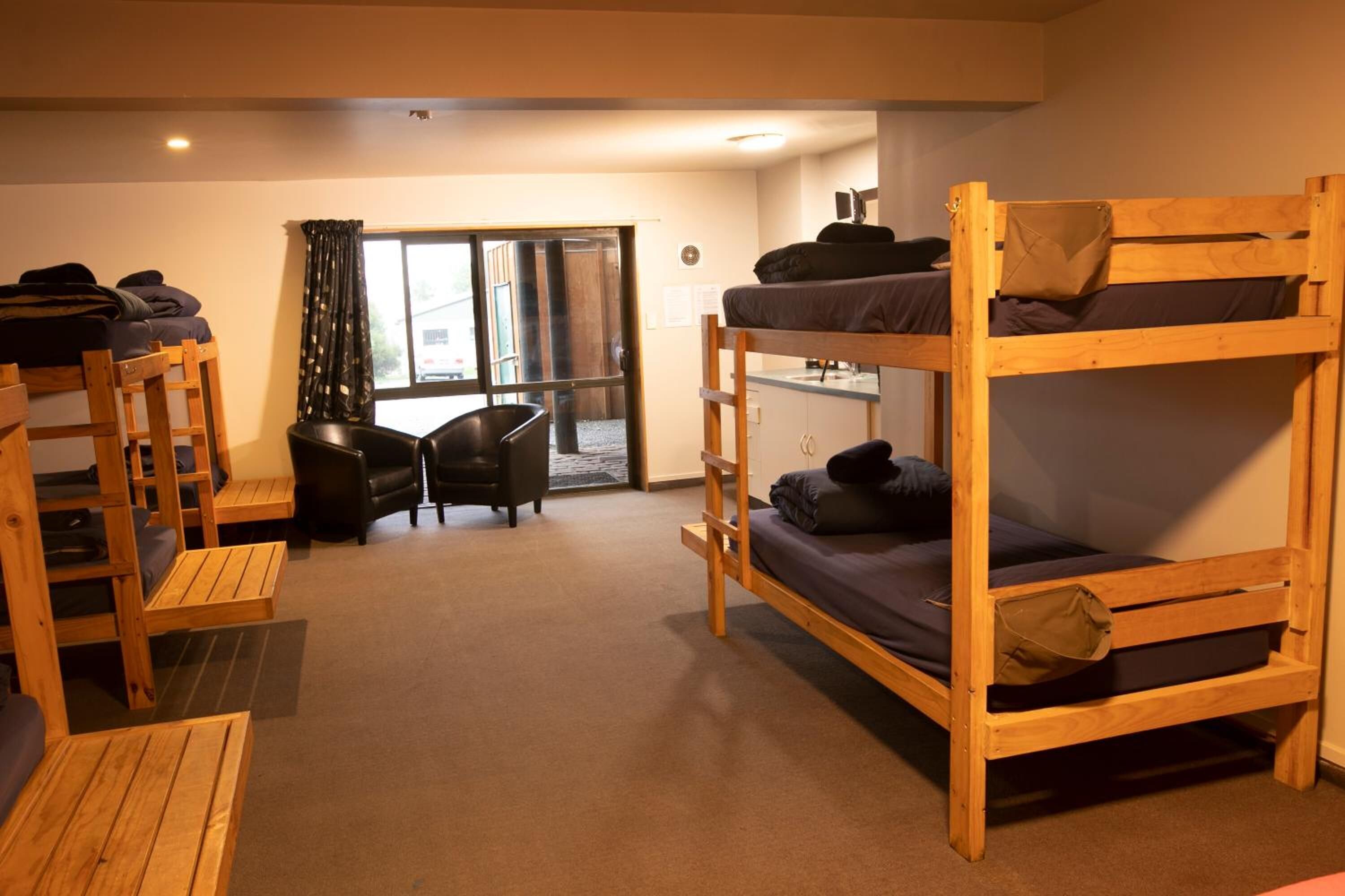 A dormitory room with bunk beds, a desk, and a chair.