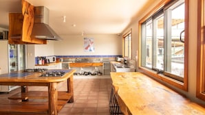 A kitchen with a wooden countertop, gas stove, and a large window. - Dusky Lodge - Hostel (Kaikoura)
