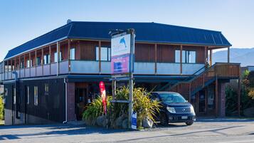 A two-story building with a blue roof, a signboard advertising a heated pool and spa, and a parked car in front.