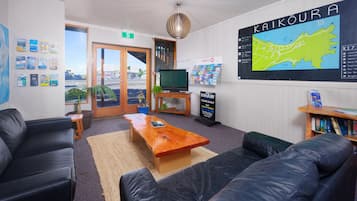 A modern hotel lobby with a large map, comfortable seating, a TV, and informational posters.