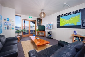 A modern hotel lobby with a large map, comfortable seating, a TV, and informational posters.
