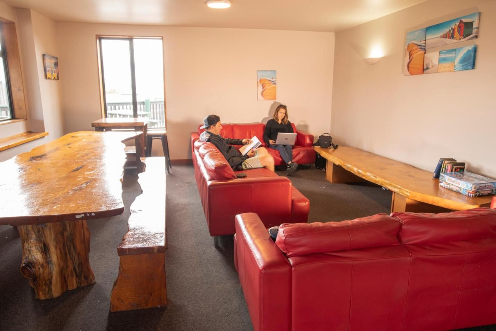A room with red leather sofas, a wooden table, and a large window.