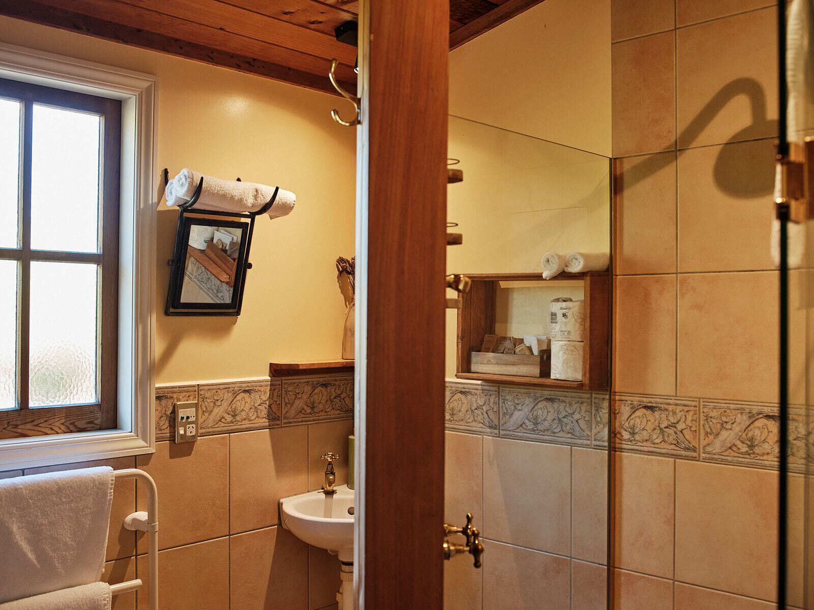 Un baño con ventana, lavamanos, espejo y toallero.