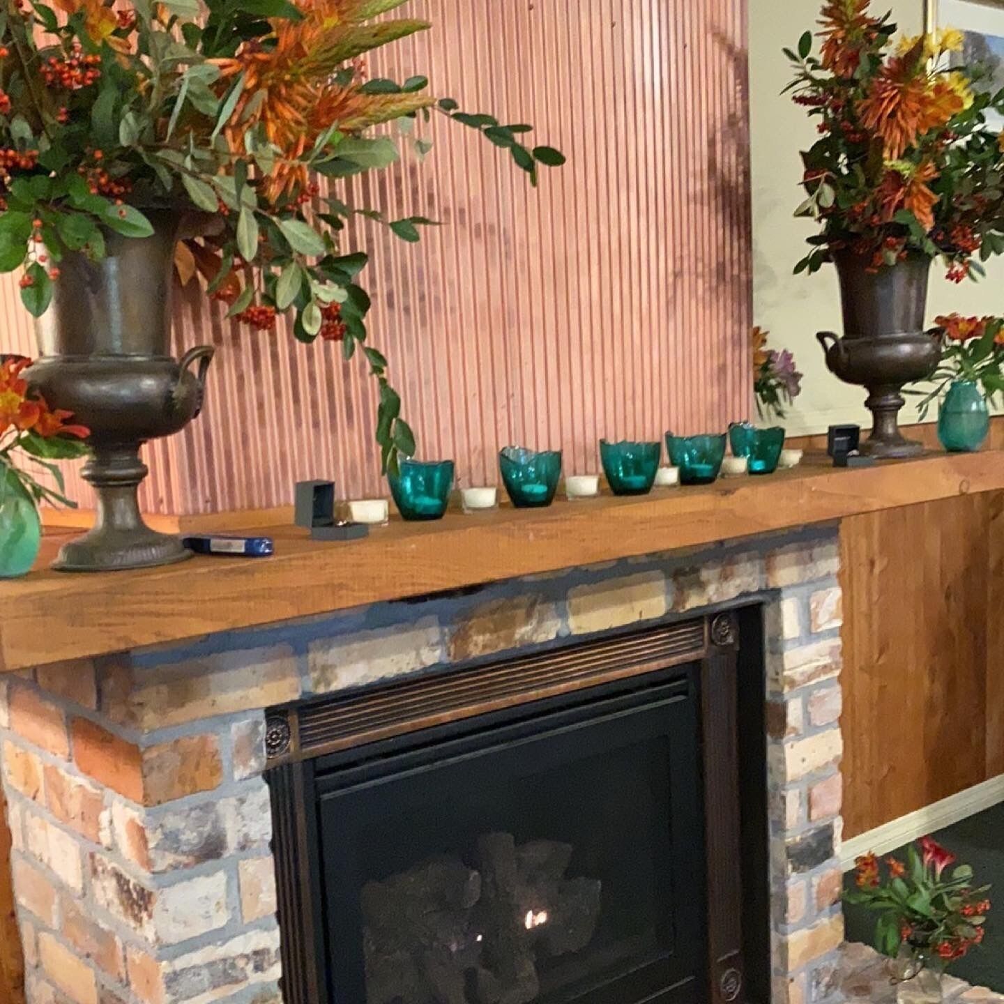 Une cheminée avec un foyer en briques, une cheminée en bois et des vases décoratifs.