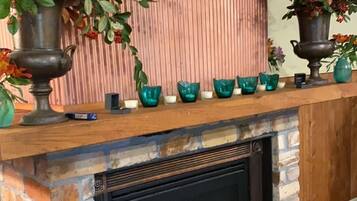 Une cheminée avec un foyer en briques, une cheminée en bois et des vases décoratifs.