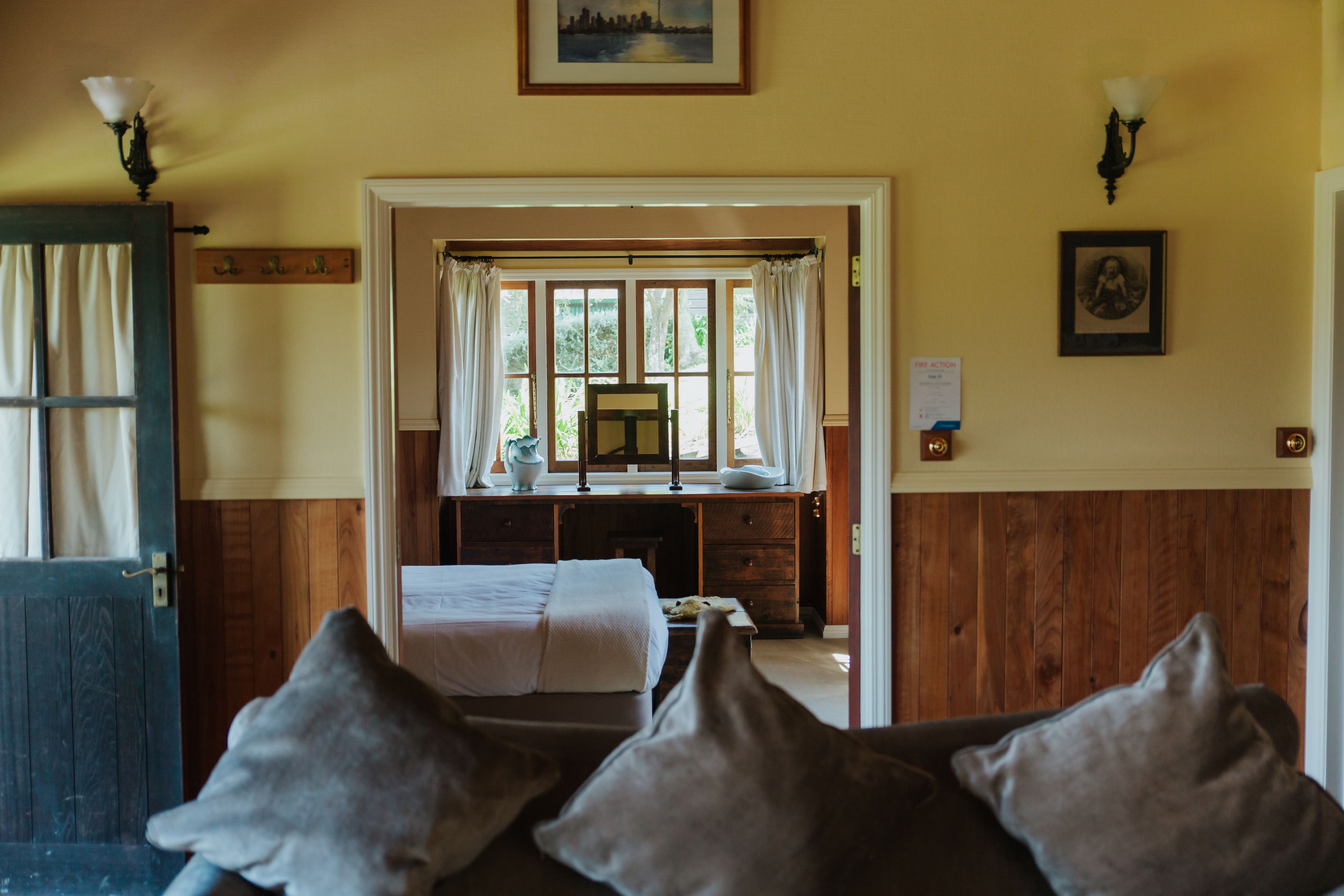 Una habitación con una cama, un escritorio y vistas a través de una ventana con cortinas.