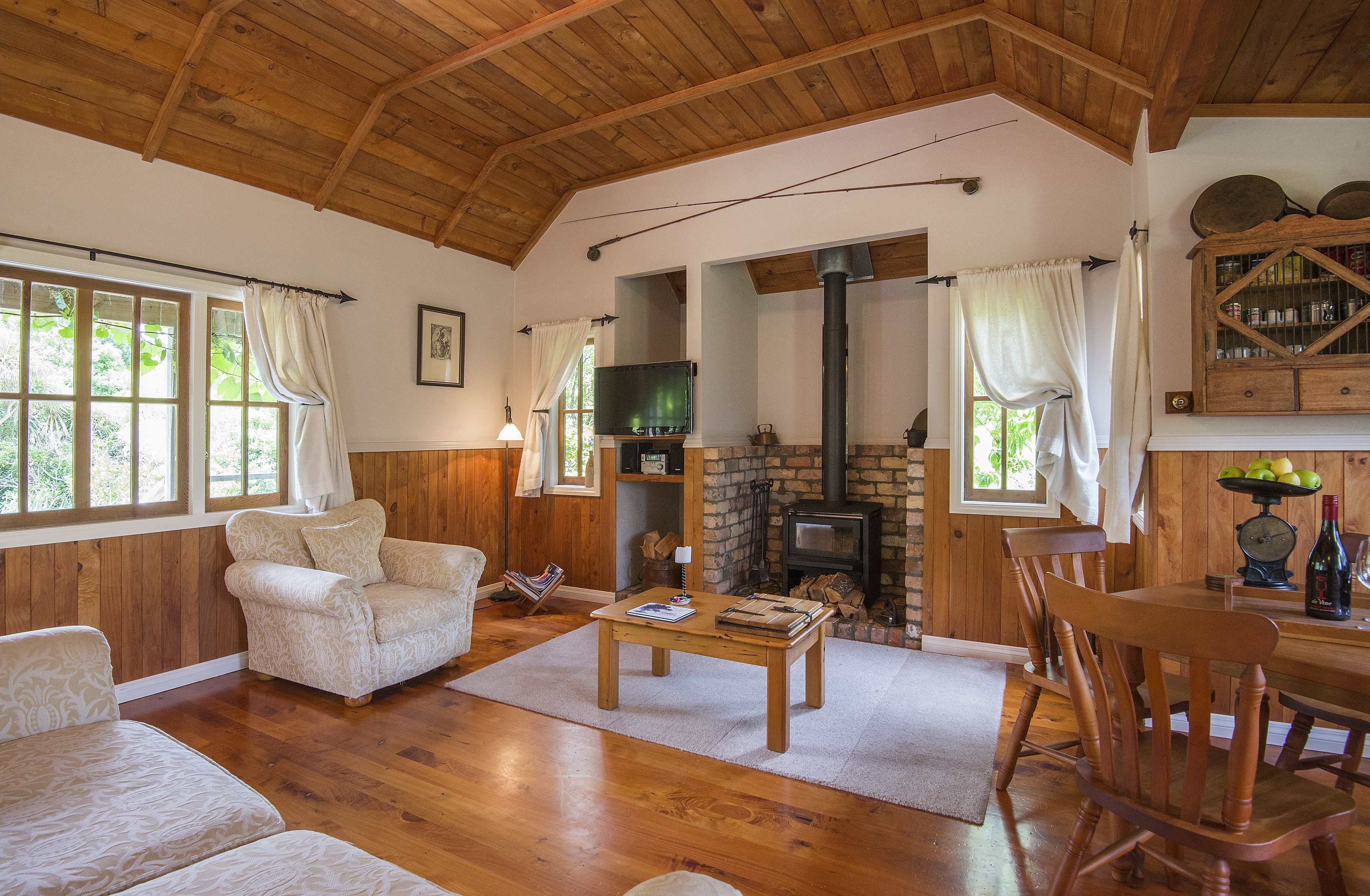 Uma sala de estar aconchegante com piso de madeira, lareira, televisão e área de jantar.