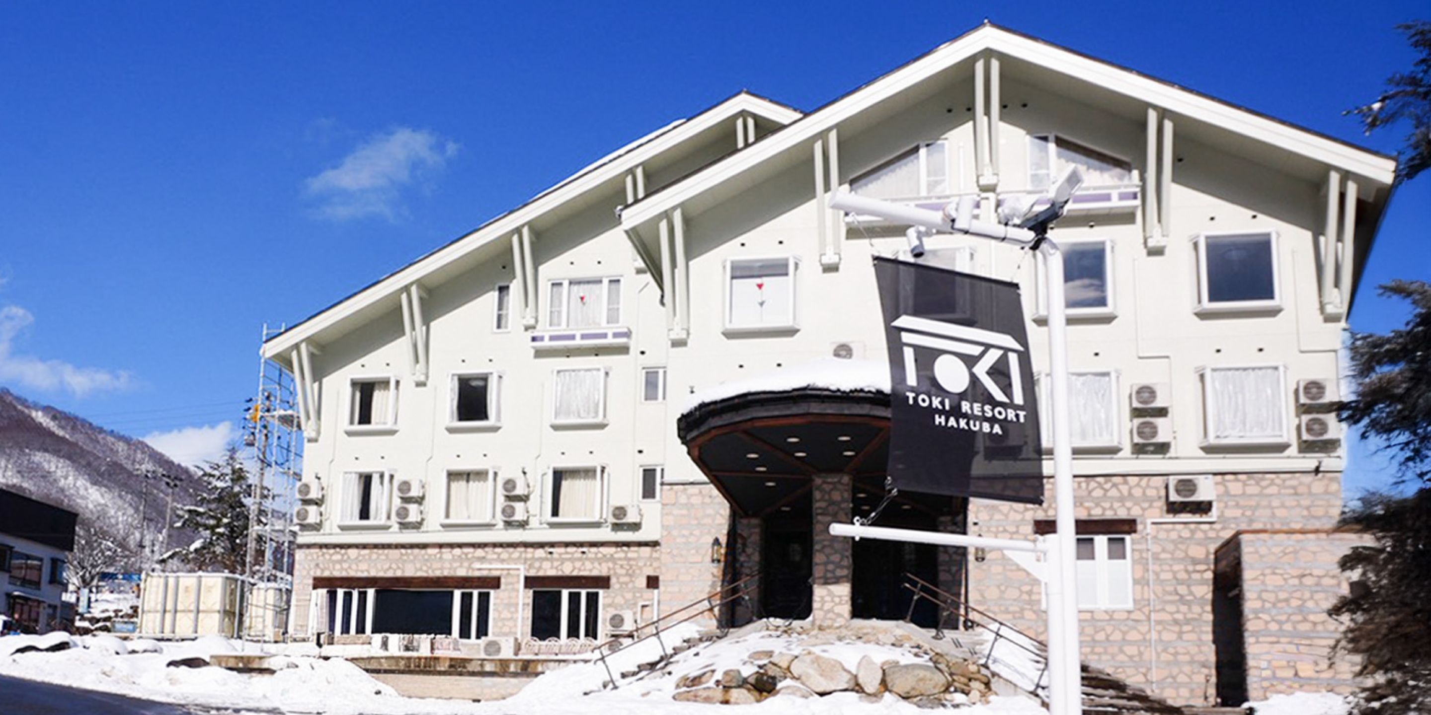 A multi-story building with a ski resort sign, a stone facade, and a clear sky.