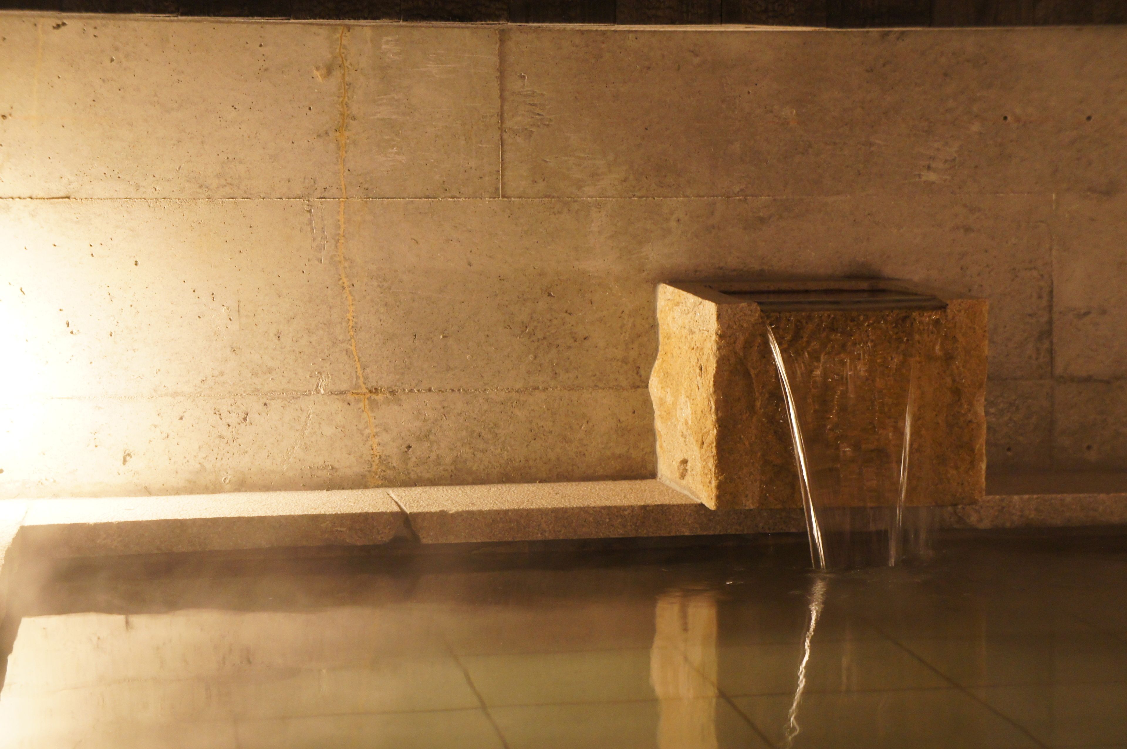 A stone structure with a water feature in a tiled room.