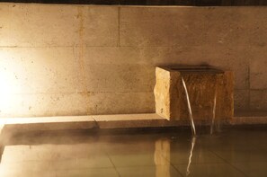 Una construcción de piedra con una fuente de agua en una habitación con suelo de azulejos.