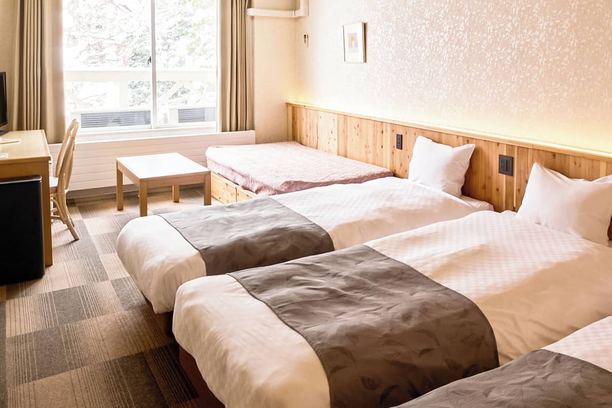 Une chambre d’hôtel avec deux lits, un bureau et une chaise.