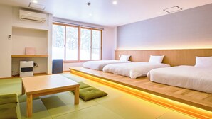 Une chambre d’hôtel avec deux lits, une tête de lit en bois, une petite table et un futon.