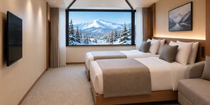 A hotel room with a large window offering a mountain view, a bed, a sofa, and a flat-screen TV.