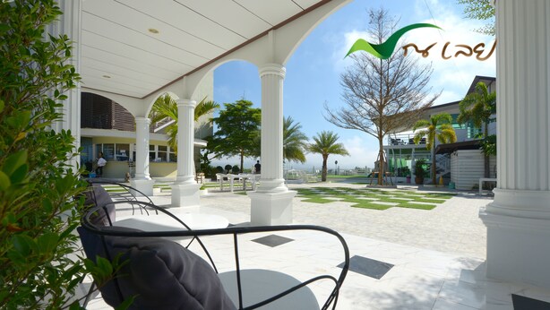 An outdoor seating area with white columns, a covered patio, and a view of the ocean. - Na Loei Boutique Resort Hotel (Mueang Loei)