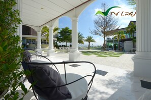 An outdoor seating area with white columns, a covered patio, and a view of the ocean. - Na Loei Boutique Resort Hotel (Mueang Loei)