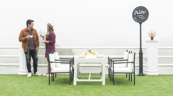 A dining area with a white table and chairs, a sign reading "Boutique Resort Hotel," and a white railing in the background. - Na Loei Boutique Resort Hotel (Mueang Loei)