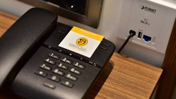 Teléfono de hotel con una tarjeta de cortesía y un cartel de Planet WiFi.