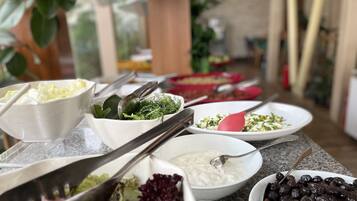A buffet table with various dishes including salads, a bowl of olives, and a bowl of yogurt.