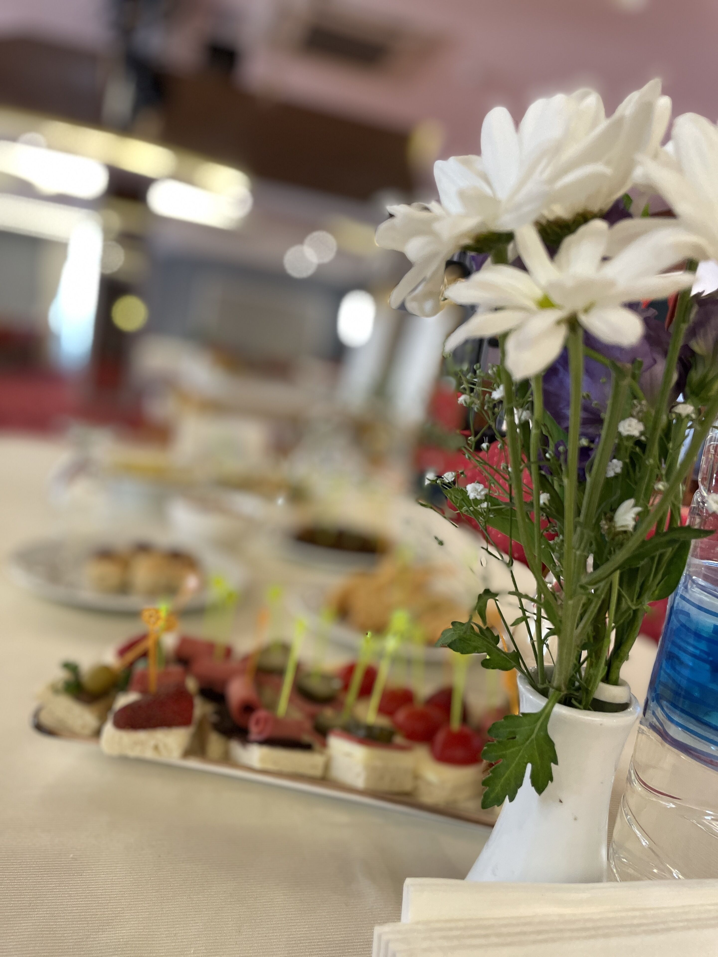 A table with various food items and a small white vase with flowers.