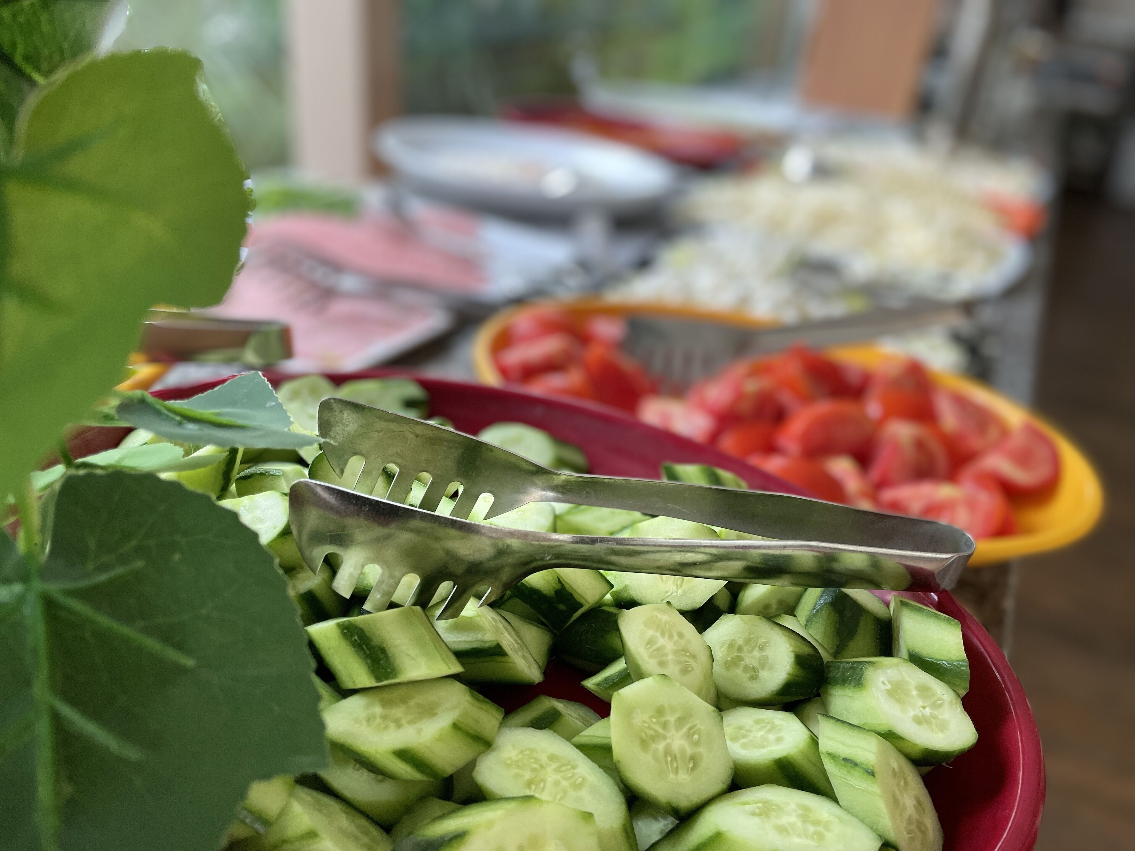 Une table de buffet proposant divers plats, notamment des tranches de concombre et des morceaux de pastèque.