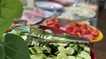 Une table de buffet proposant divers plats, notamment des tranches de concombre et des morceaux de pastèque.