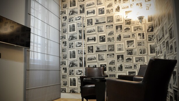 A room with a patterned wallpaper, a wooden floor, and a seating area with chairs. - Place 24 Suites & Wellness (Rome)