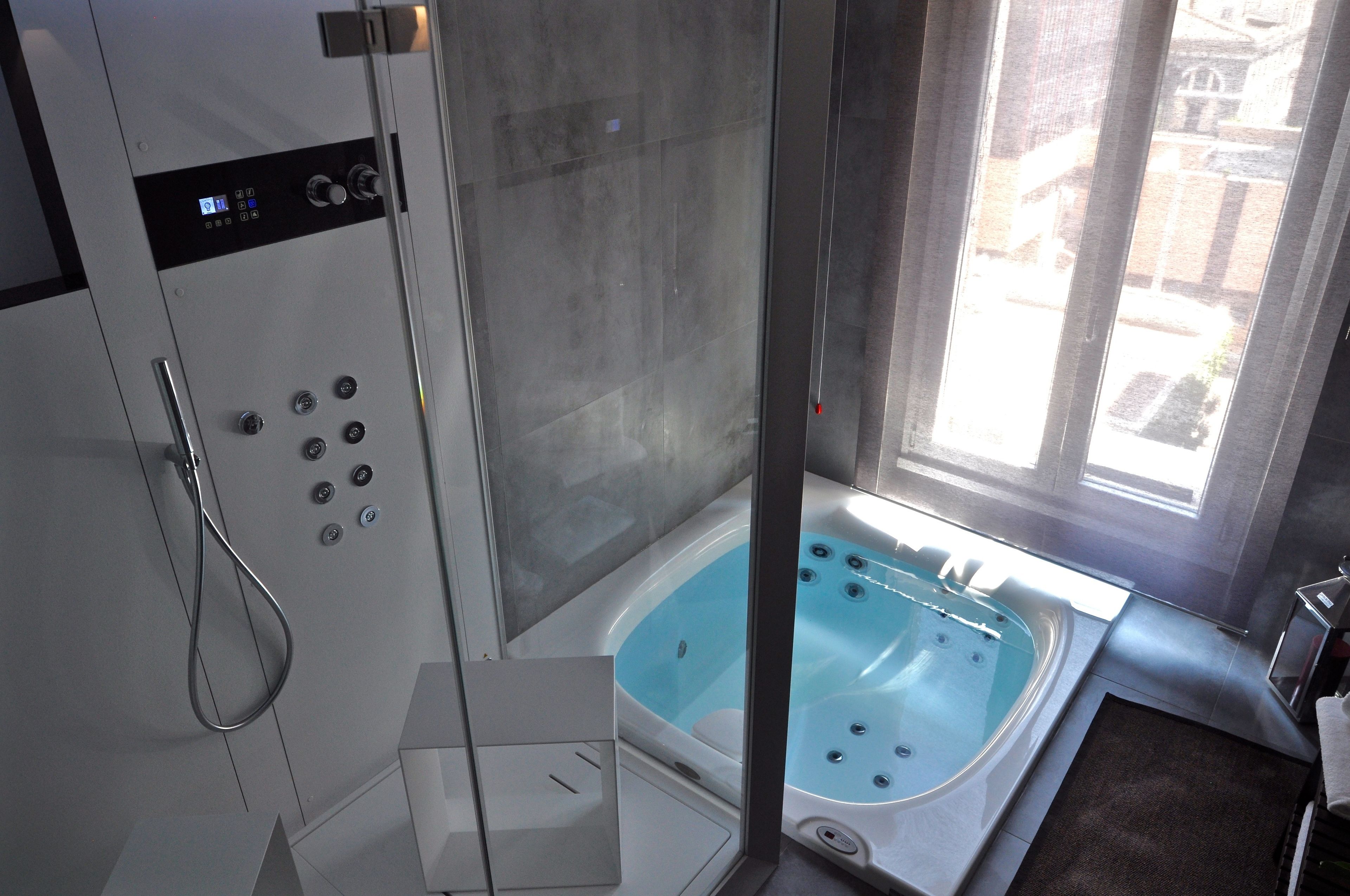 A modern bathroom with a glass-enclosed shower, a freestanding bathtub, and a window providing natural light.