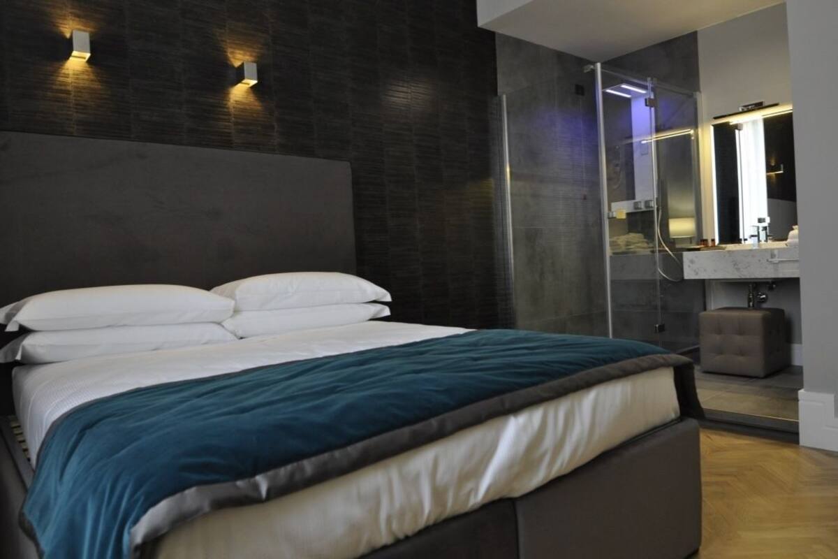Une chambre moderne avec un grand lit, une cabine de douche en verre et une coiffeuse intégrée avec un miroir.