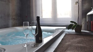 A spa room with a hot tub, two glasses, and a bottle of wine. - Place 24 Suites & Wellness (Rome)