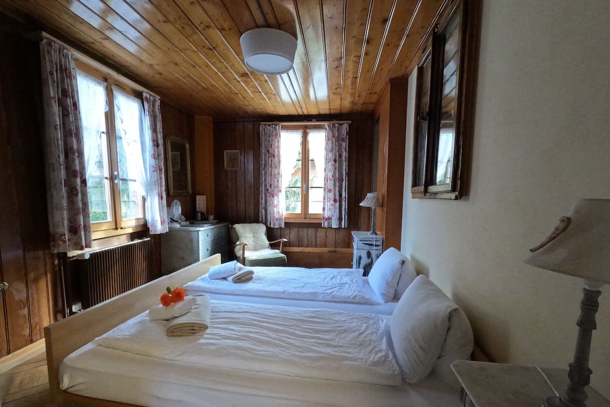 Habitación de cabaña de madera con dos camas, un escritorio y una silla.