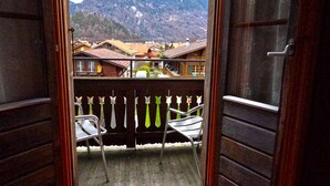 Un balcon ouvert donnant sur une montagne et un village.