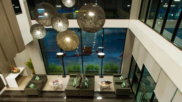 A modern lobby with a pool view, seating areas, and decorative spherical lights. - Leosor Hotel (Nakhon Ratchasima)