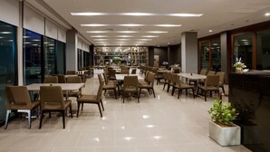 A spacious indoor dining area with multiple tables and chairs, large windows, and a modern ceiling design. - Leosor Hotel (Nakhon Ratchasima)