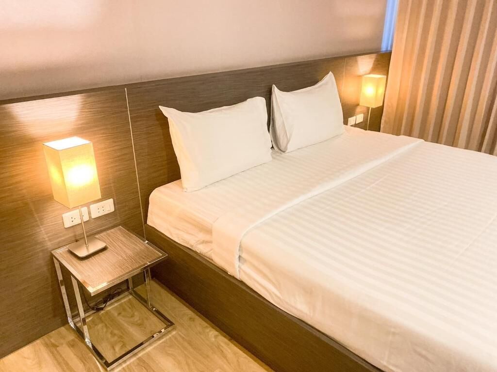 A hotel room with a bed, bedside lamps, and a nightstand.