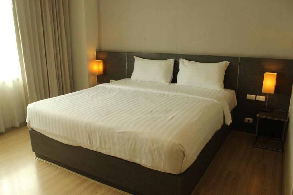 Een hotelkamer met een groot bed, twee bedlampen en een houten vloer.