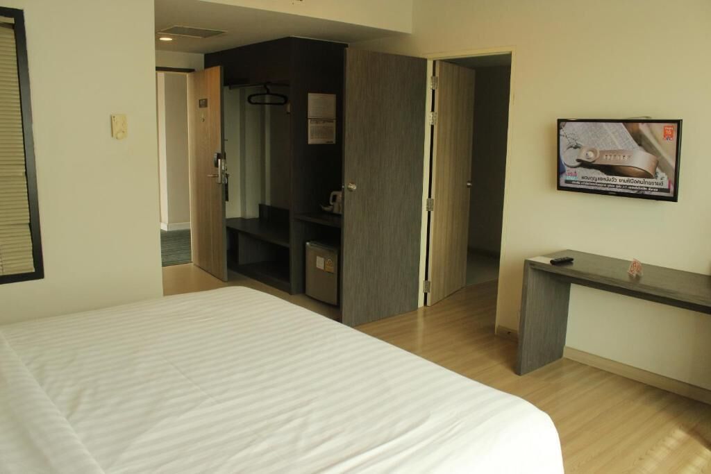 A hotel room with a bed, a desk, a television, and a wardrobe.