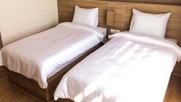 A double bed with white bedding in a room with wooden headboard and nightstand.