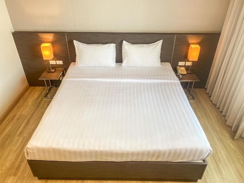 Quarto de hotel com uma cama grande, duas mesas de cabeceira com luminárias e uma cabeceira.